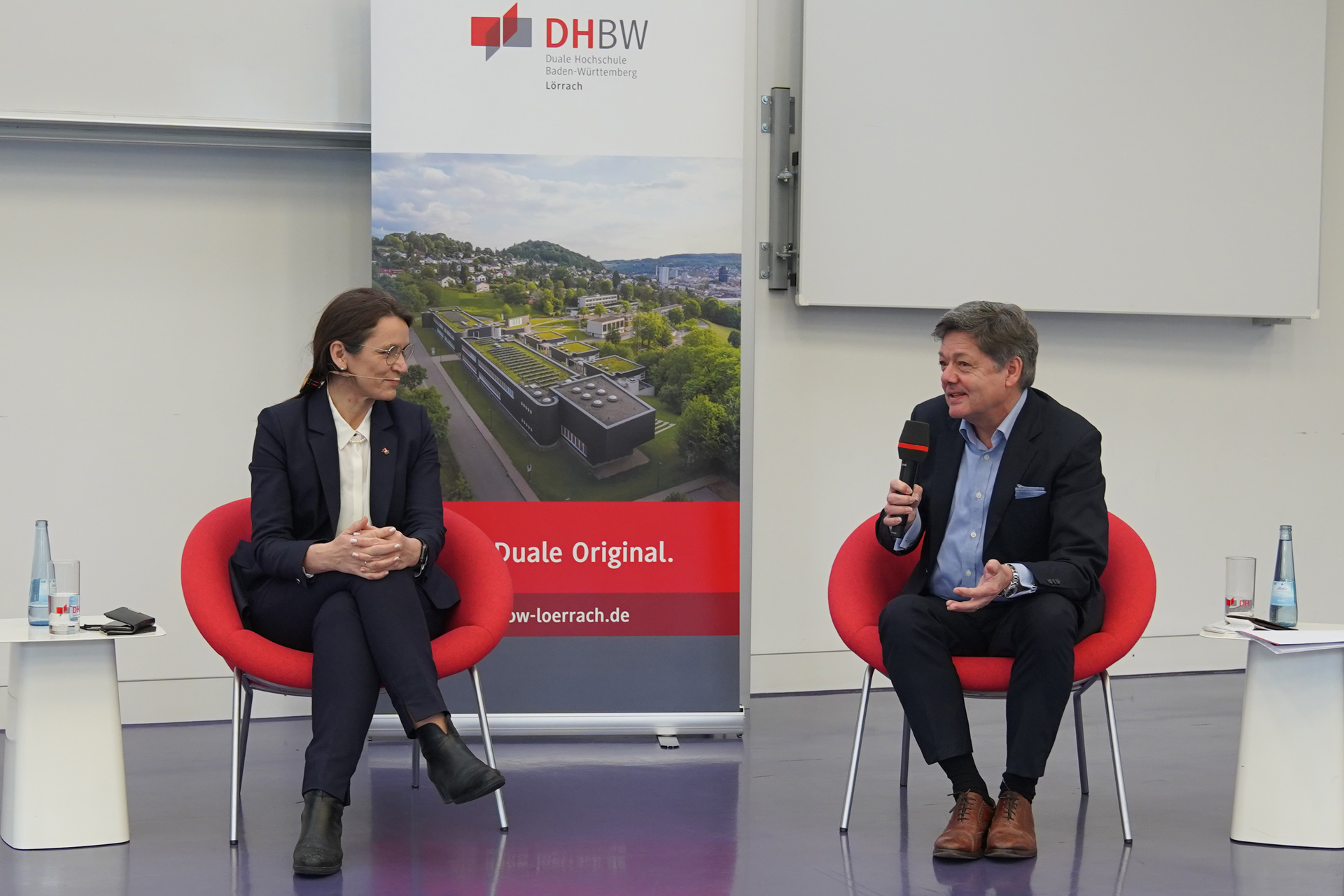 DHBW Präsidentin Prof. Dr. Martina Klärle und der Rektor der DHBW Lörrach  Prof. Dr. Theodor Sproll sitzen auf zwei roten Stühlen und führen ein Interview