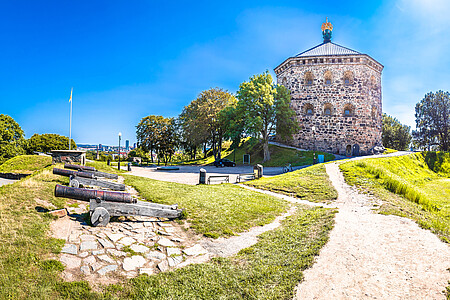 Ansicht der historischen Festung Skansen Kronan in Göteborg mit alten Kanonen im Vordergrund an einem sonnigen Tag.