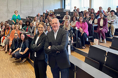 Gruppenfoto im Hörsaal der DHBW Mannheim während der FIREtalk Conference 2025. Zahlreiche internationale Teilnehmende sitzen und stehen lächelnd zusammen, zwei Konferenzleitende posieren vorne im Bild.