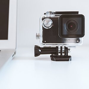 Foto einer Kamera mit einem Objektiv, die neben einem Laptop steht.