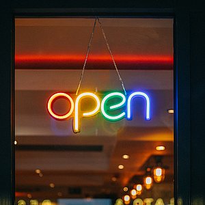 Foto eine Leuchtschrift, die das Wort "open" darstellt. Jeder Buchstabe hat eine andere Farbe.