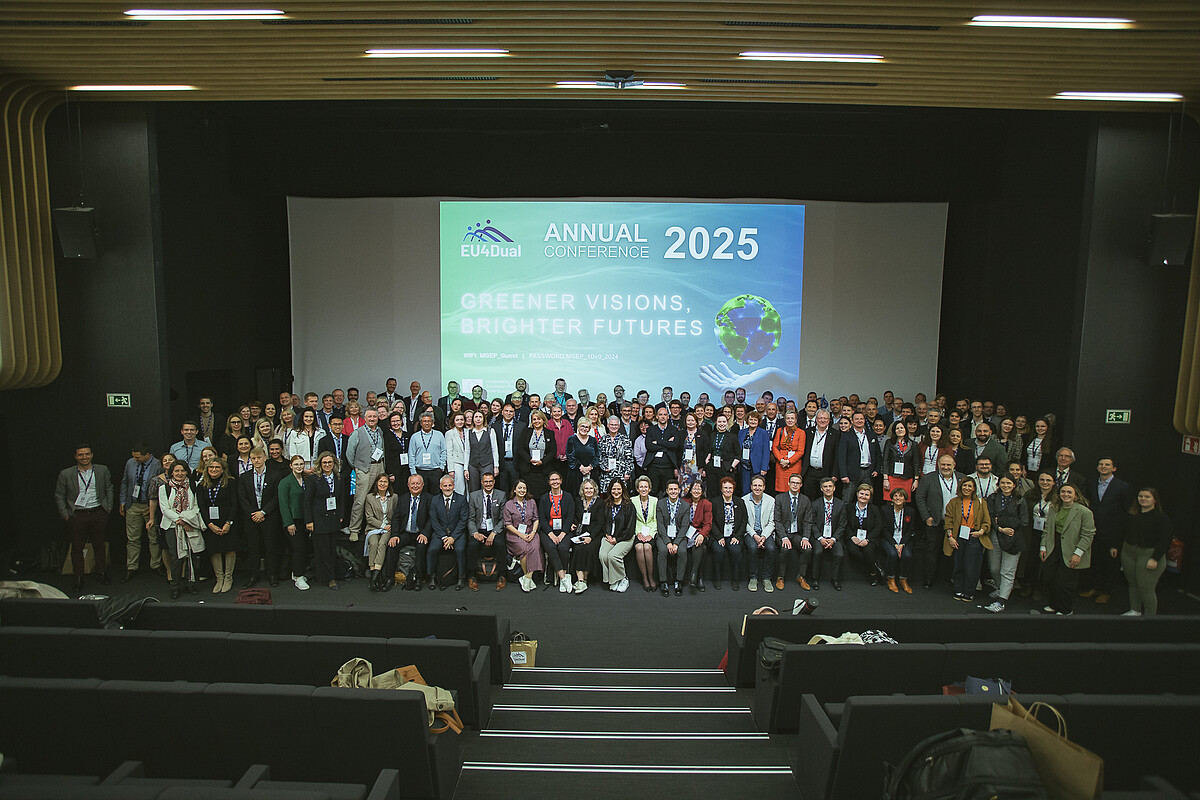Gruppenbild mit Konferenzteilnehmer*innen im Hörsaal vor einer Leinwand