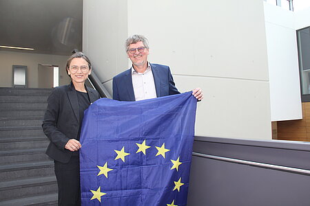 Prof. Dr. Martina Klärle und Prof. Dr. Raimund Hudak halten eine Europa-Flagge