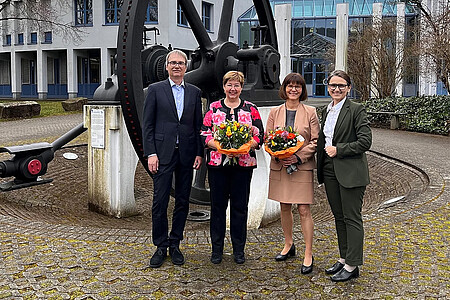 Vier Personen auf dem Außengelände der DHBW Mosbach, zwei mit Blumenstrauß.