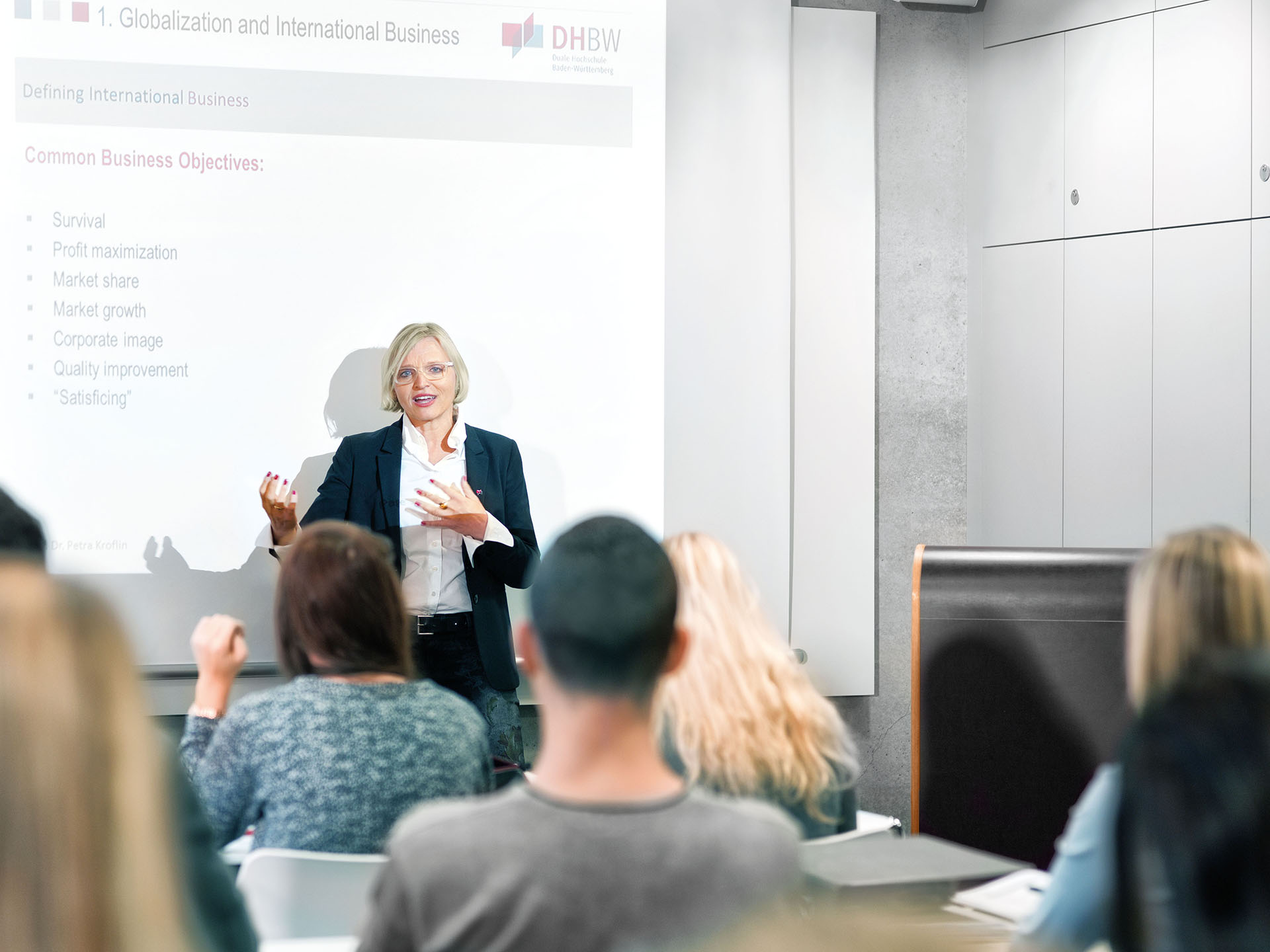 Eine Professorin hält eine Vorlesung vor Studierenden der DHBW. Im Hintergrund ist eine Powerpoint Folie zu sehen.