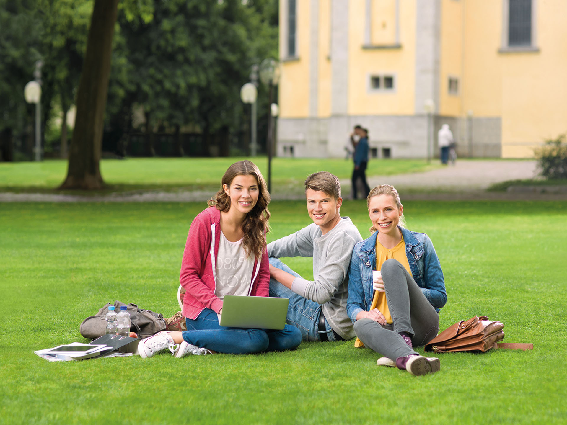 Studierende sitzen auf einer Wiese am Campus Bad Mergentheim