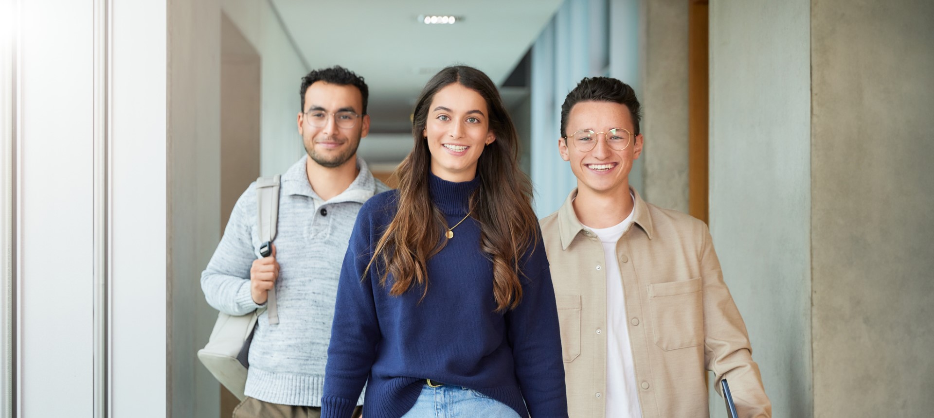 Drei Studierende laufen einen Gang entlang