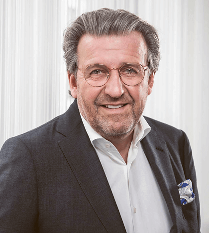 Portraitfoto Herr Wolf in Anzug vor grauer Wand